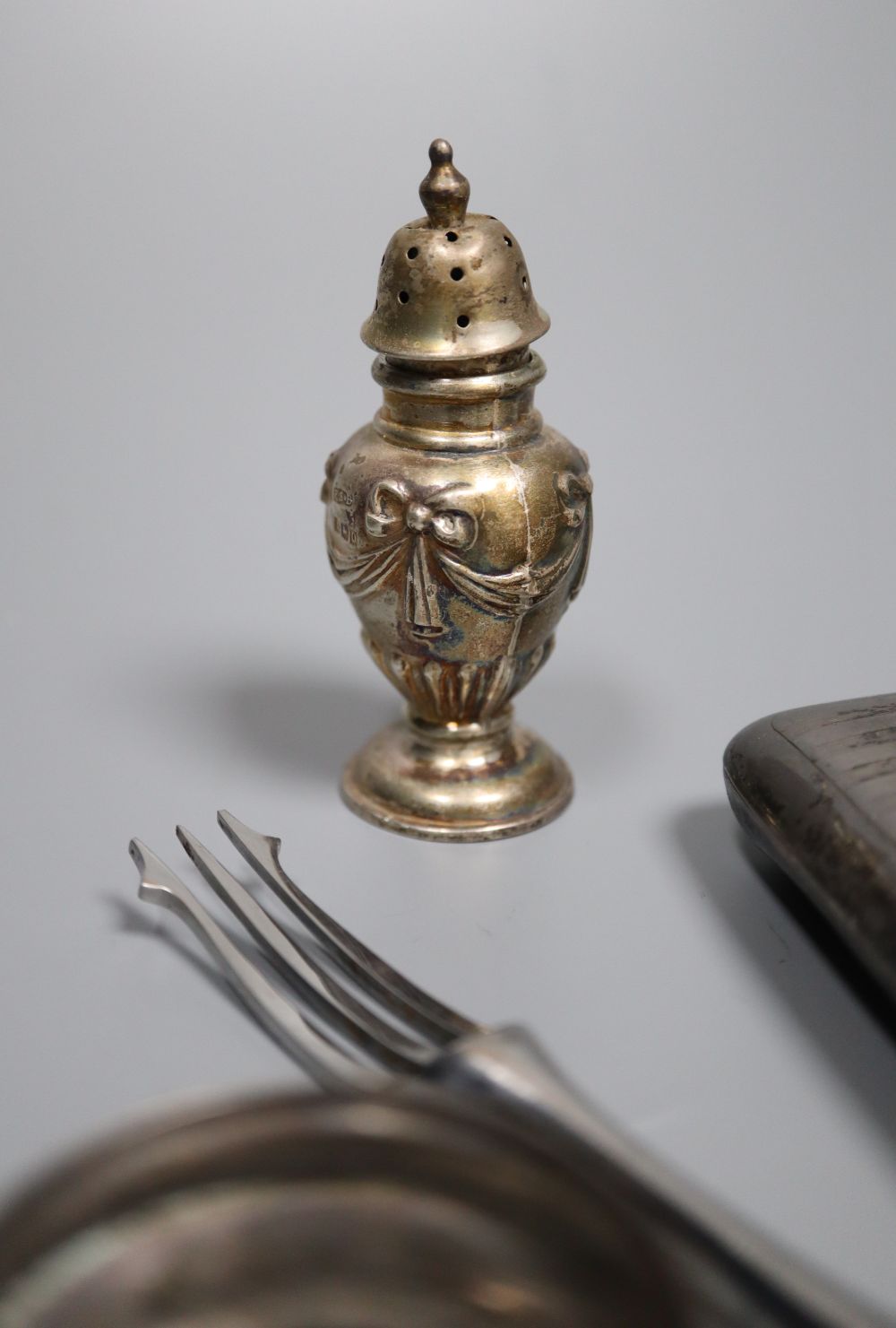 Nine assorted silver napkin rings, a pair of silver pepperettes, a silver cigarette case and pair of silver handled servers.
